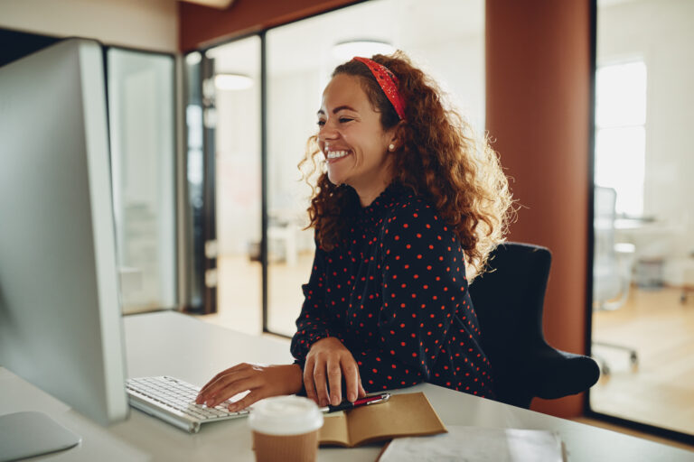 Laughing young businesswoman working on her office computer